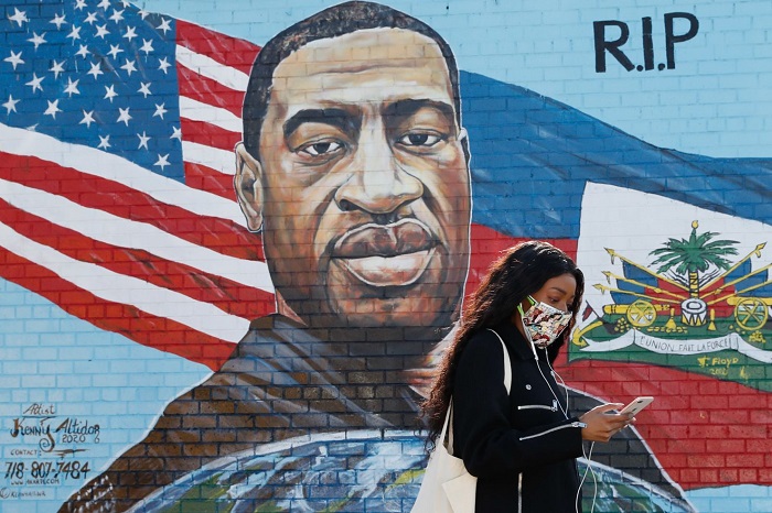 A street mural showing George FLoyd's face against an American flag, with the letters 'RIP'.