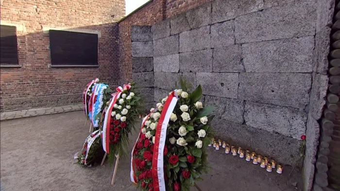 image of wreaths laid at a wall at Auschwitz